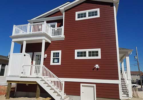 Two story home with brand new red vinyl siding installed by Quality A+ Home Improvements